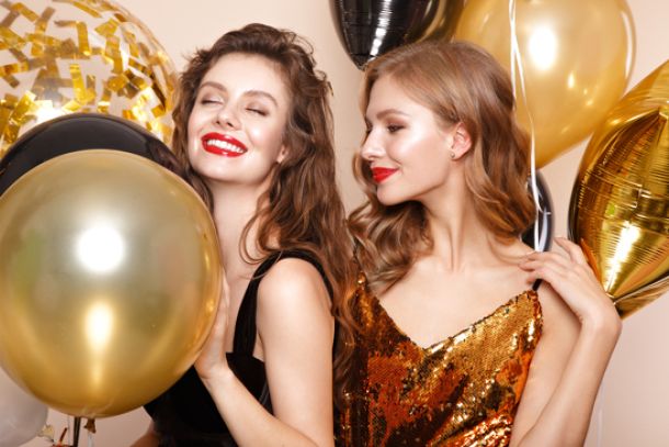 Zwei Frauen mit goldenen und schwarzen Ballons mit Helium gefüllt