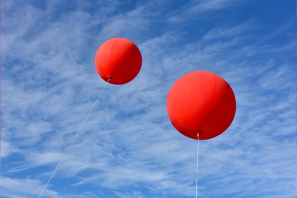 Zwei rote Riesenballons mit Helium gefüllt, schweben im Himmel